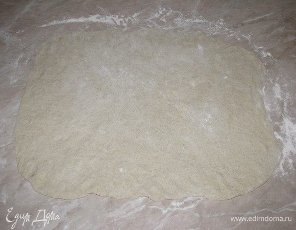 Стол хорошо подпылить мукой. Выложить подошедшее тесто, присыпть мукой и руками растянуть в прямоугольный пласт. Скалку использовать не нужно, так как тесто очень мягкое и легко растягивается.