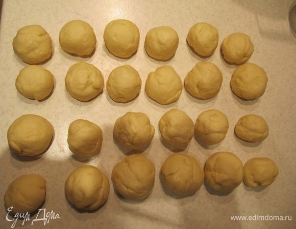 Поднявшееся тесто обмять руками, чтобы выпустить лишний воздух, и разделить на 4 части. Затем каждую часть разделить еще на 6 частей, скатать их в небольшие шарики. Старайтесь, чтобы шарики получались приблизительно одинакового размера. Всего получится 24 шарика.