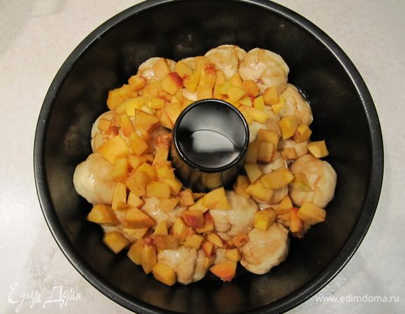 А затем выложить кусочки персика. Накрыть форму пленкой и отправить в теплое место на повторную расстойку на 35 минут.