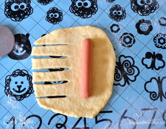 Использовать лучше всего небольшие, детские сосиски. У нас они достаточно тонкие. Думаю, что если они по толщине ближе к "классическим" сосискам, то так даже лучше. Итак, раскатать колобок из теста в лепешку. На одну сторону положить сосиску, вторую половинку нарезать полосками.