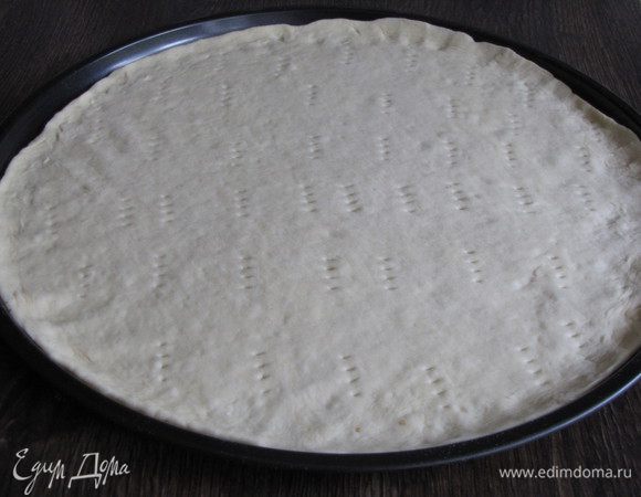 Готовое тесто обмять, на присыпанном мукой столе раскатать в круг и выложить в форму для пиццы (у меня диаметр формы 30 см.) Или можно просто выложить на противень. 