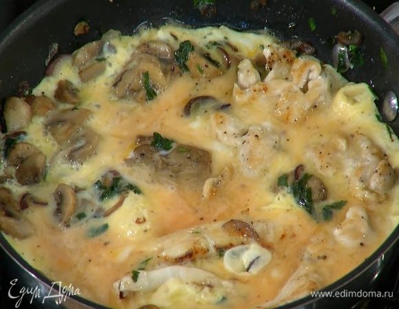 Влить яичную массу в сковороду с курицей и грибами, накрыть крышкой и готовить 3–4 минуты.