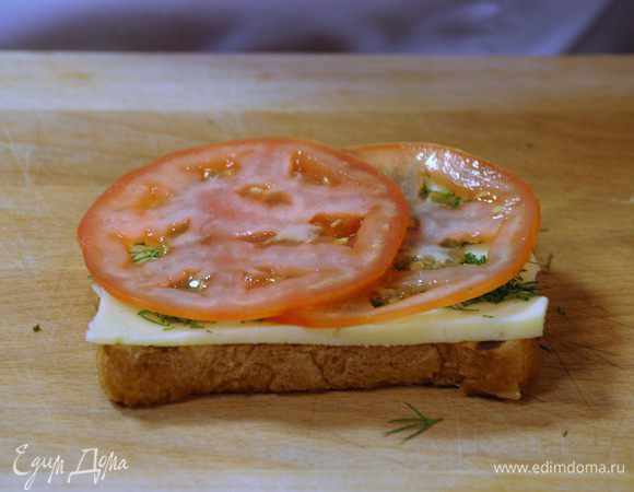 На тост выложить сыр, посыпать рубленым укропом, добавить нарезанный помидор. Закрыть вторым тостом и разрезать пополам. 