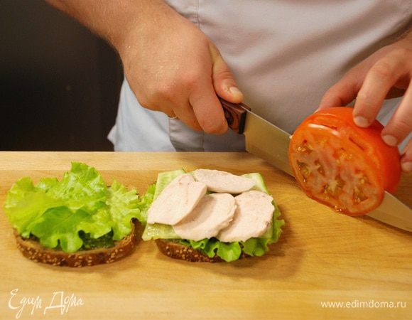 На сэндвич выложить листья салата, нарезанный огурец, куриное филе, а затем ломтики помидора. 