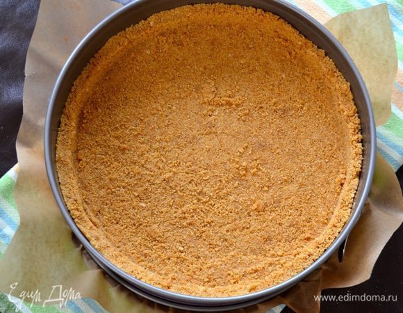 Выложить полученную крошку в разъемную форму диаметром 24 см (можно положить на дно пекарскую бумагу). Разровнять по всей форме и сформировать бортик.