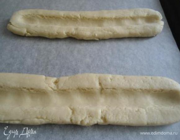 Добавляем муку, крахмал и разрыхлитель, замешиваем быстро тесто  и делим его на две части, катаем колбаски( длина у меня около 20 см) и посередине делаем пальцем углубление. Выкладываем на бумагу для выпечки,ничем не смазываем.