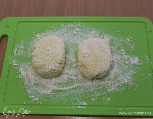 Насыпать кукурузную муку для обсыпки на доску. Сформировать сырники. 