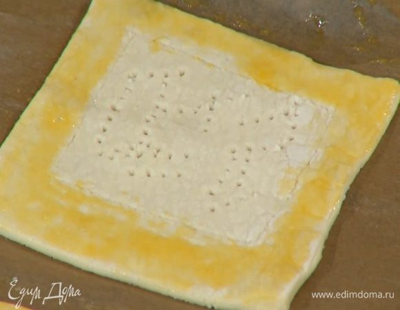 Желток перемешать с солью и смазать бортики теста, внутреннюю часть квадратиков часто наколоть вилкой.