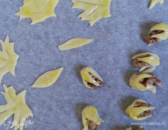 Четвертинки грецкого ореха завернула в маленькие треугольнички теста.