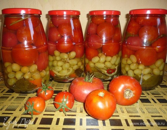 На дно каждой банки выкладываем – пряности, листья хрена, листики вишни, смородины, лавровые листики, гвоздику, зубчики чеснока. Затем аккуратно укладываем виноград вместе с веткой, на виноград кладем помидоры. В свободное пространство кладем полоски сладкого перца. 
