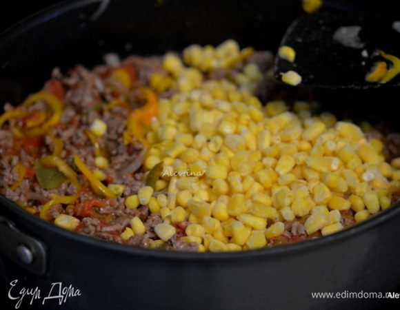 Вернуть сковороду на огонь. Добавить овощную сальсу домашнюю или покупную, нарезанные баночные томаты в собственном соку, замороженную кукурузу. Помешивать и готовить 8 мин.