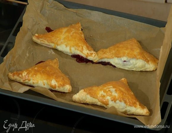 Противень выстелить бумагой для выпечки, выложить слойки и выпекать в разогретой духовке 20 минут.