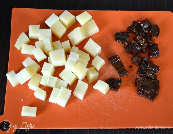 Тем временем подготовить сыр и вяленые томаты для начинки. Они должны быть комнатной температуры, поэтому в случае необходимости, достаньте их заранее из холодильника... Сыр нарезать небольшими кубиками, помидоры - небольшими кусочками (можно использовать вяленый помидорки-черри!). 