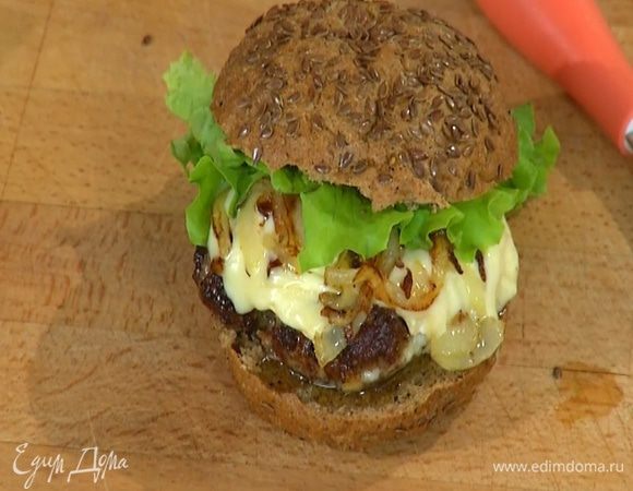 На одну половину каждой булочки выложить котлету, сверху поместить обжаренный лук и пару листьев салата. Накрыть второй половиной булочки.