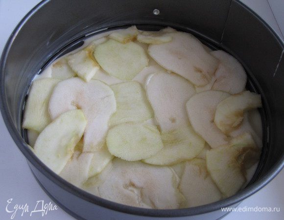 На дно разъемной формы диаметром 20 см положить пергамент, смазанный маслом. Выложить немного теста, равномерно распределить с помощью лопатки. Затем слой груш и яблок.