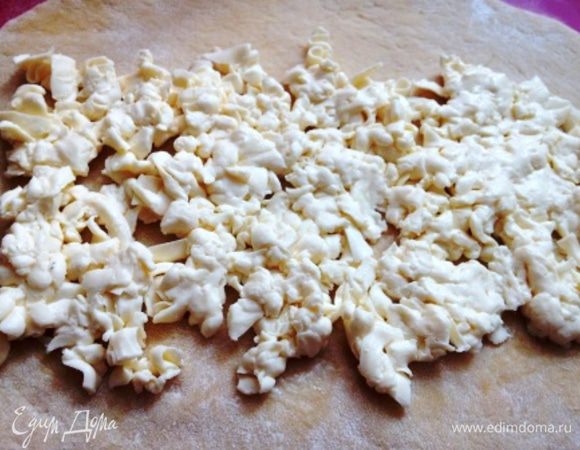 Тесто раскатать в прямоугольник и густо выложить на него тертый на терке плавленый сырок.