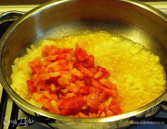 Теперь начинаем готовить начинку. С крупы слить воду. На оливковом масле в глубокой сковороде обжарим до прозрачности лук. Добавим пол-ложки томатной пасты и помидор. Слегка обжарим и погасим огонь под сковородой. 