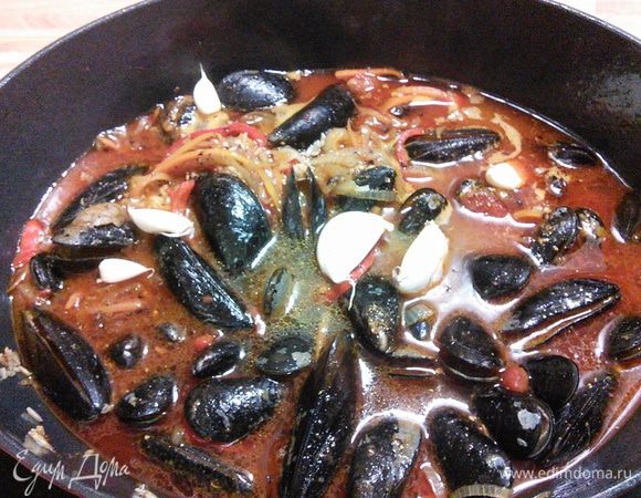 Теперь очередь мидий, уже очищенных и вымытых. Если у вас замороженные, то их желательно заранее разморозить. Залить горячим бульоном (его может уйти чуть больше, главное, чтобы был покрыт жидкостью рис). Чеснок разделить на дольки и не очищая от шелухи вымыть и добавить в плов, посолить и поперчить по вкусу. 