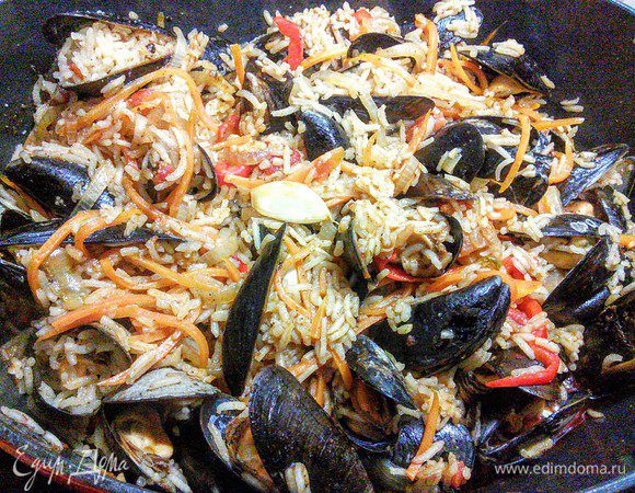 Аккуратно перемешать, кастрюлю накрыть крышкой и томить плов на среднем огне до готовности риса. По необходимости можно добавить бульон. 