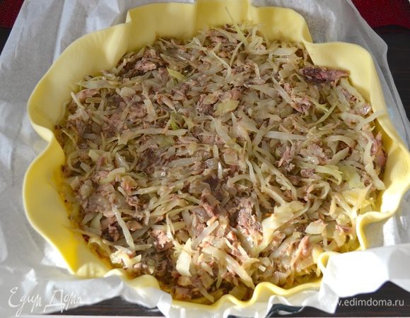 Слоенное тесто (у меня готовое, уже раскатанное) выложить в форму для запекания (диаметр 26 см, но может быть и больше). Я оставляю пекарскую бумагу, на которой раскатано тесто. Слегка наколоть вилкой и выложить начинку. Разровнять.