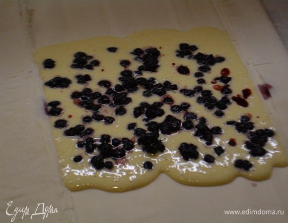 Противень застелить пекарской бумагой и выложить 3 листа. Смазать их растительным маслом (я это сделать забыла). На середину вылить полпорции теста. И посыпать ягодами (если замороженные, предварительно разморозить и слить жидкость). Короткие края загнуть и придавить пальцами.