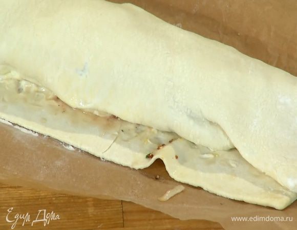 На одну сторону теста ближе к краю выложить начинку, оставшийся свободный край смазать яйцом и свернуть все в рулет.