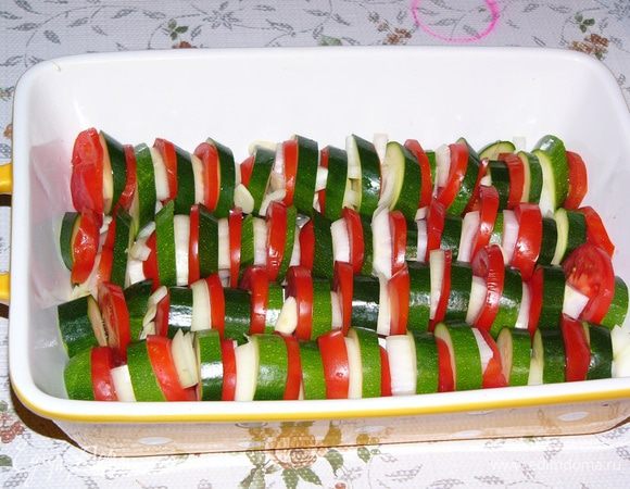 Лук и чеснок очистить. Чеснок нарезать пластинами, лук - полукольцами или, если очень крупный, четвертинами. Помидоры и цукини вымыть и нарезать кольцами. Уложить рядами в блюдо для запекания цукини-помидор-лук. В просветы положить пластины чеснока. 