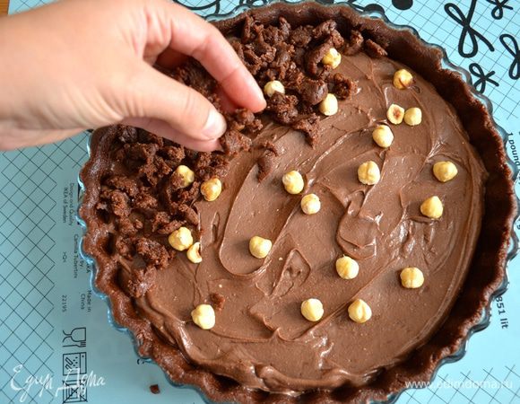 Разложите по крему несколько орешков. Теперь достаньте из холодильника оставшееся тесто...и на этот раз мы не будем его раскатывать! А просто, отделяя пальцами небольшие кусочки теста, покрошим его поверх пирога!