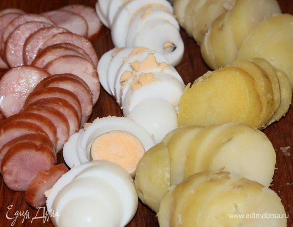 Отвариваем картофель в мундире, яйца вкрутую. Чистим картофель, яйца и колбасу, нарезаем все кольцами толщиной приблизительно 7 мм.