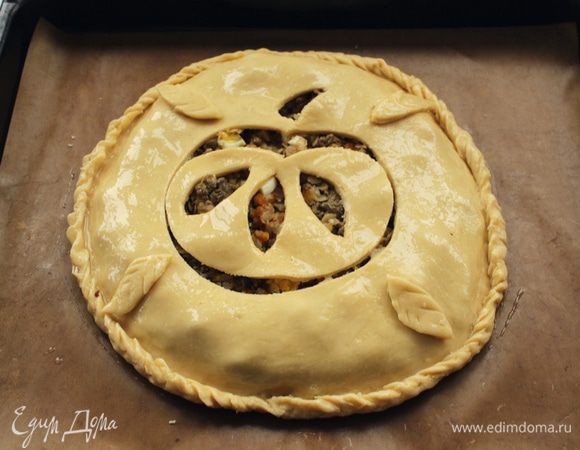 Накрыть пластом раскатанного теста, размером поменьше. Защипнуть края, смазать пирог яйцом и сделать фигурные надрезы.
