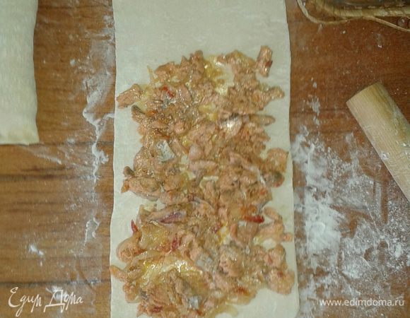 Раскатать пласт теста на присыпанной мукой поверхности, выложить на него остывшую начинку. Скрутить рулетом и залепить края. Яйцо взбить, обмазать рулетики.