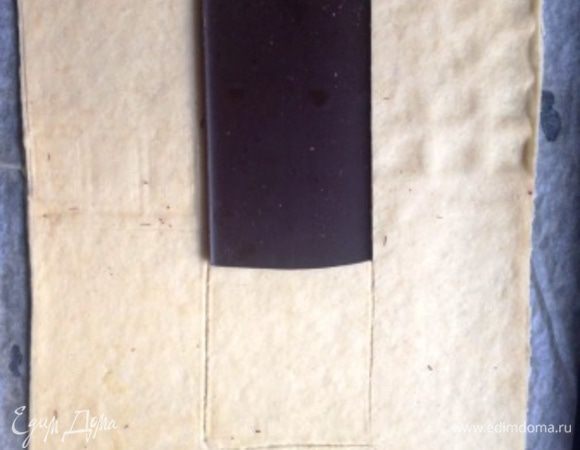 Перенести прямо на пергаменте на противень.
Уложить 1,5 плитки шоколада ровно в центре полученного прямоугольника.
Обвести контур.