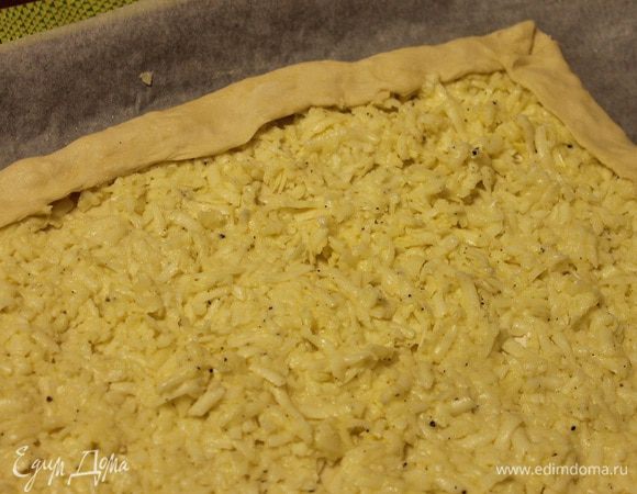 Сверху теста выложить начинку и разровнять ее руками.