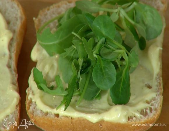 Булку разрезать пополам вдоль, смазать обе половинки майонезом и уложить на них салатные листья.