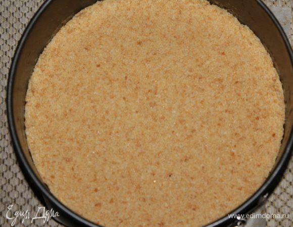 Дно разъемной формы выстилаем пергаментом, выкладываем сухари и плотно трамбуем.