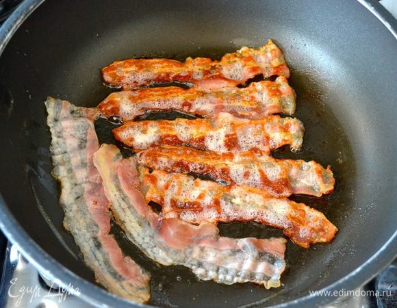 Тем временем в другой сковороде обжарить полосочки бекона. Выложить на салфетку.
