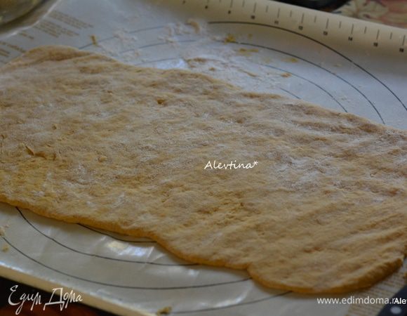 Разогреть духовку до 190 гр. Смазать маслом 3 формы для запекания. Выложим тесто на припыленную мукой рабочую поверхность. У меня ушло примерно 1-1/2 стакана, тесто берет много муки. Разделить тесто на 2 равные части. Одну часть выложить прямоугольником, мне например не понадобилось даже скалки, получилось все руками. Тесто послушное , слегка липкое. Не тонко.