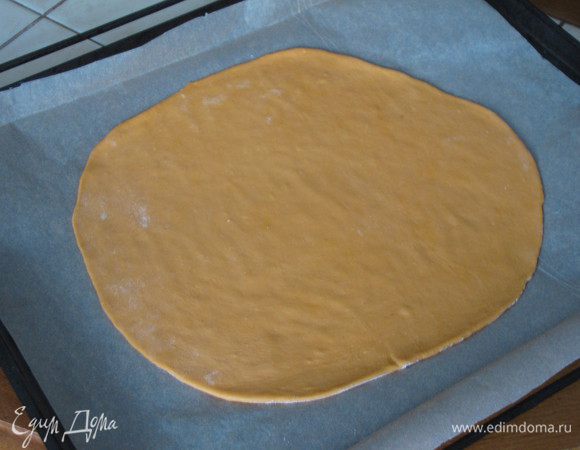 Достать тесто из холодильника. Отделить небольшой кусочек для декора. Оставшееся тесто разделить на две равные части. Одну часть раскатать тонко в круг на припыленном мукой столе. Аккуратно перенести на противень, застеленный пекарской бумагой.