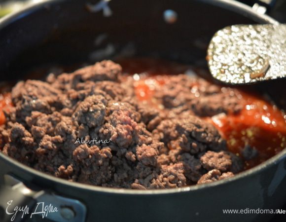 Обжарить на этой же сковороде луковицу тонко порезанную 5 минут затем чеснок раздавленный 2 минут. Добавить томатную пасту и помидоры порезанные в соку, итальянские специи, лавровый лист, соевый соус, чесночный порошок, специя Монреаль, соль и перец. Вернуть говяжий фарш, перемешать. Закрыть крышкой и тушить 20-25 минут.