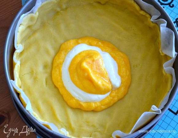 Духовку включить разогреваться на 180 градусов. Достать форму с тестом из холодильника и выкладывать в центр пирога ложками поочередно тыквенную и творожную начинки.