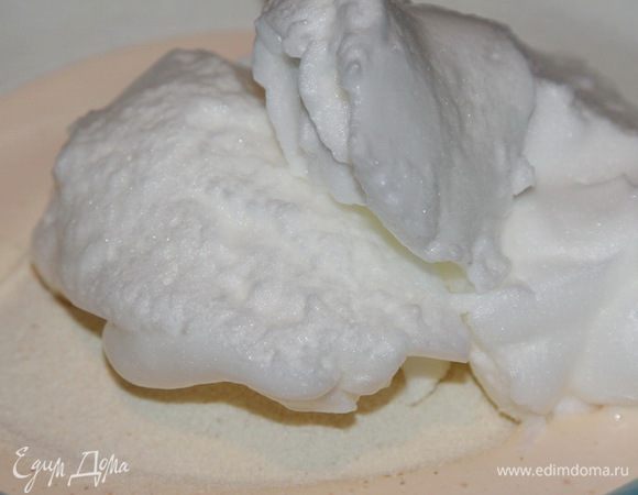 Взбитые желтки перекладываем в миску, сверху высыпаем манку и ванильный сахар. Выкладываем половину взбитых белков и аккуратно вмешиваем в желтки и манку.