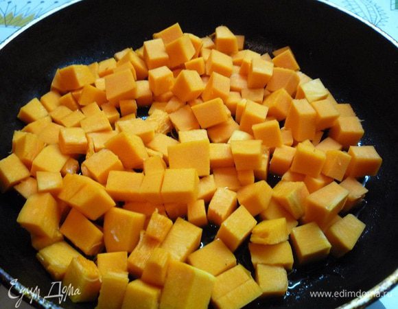 В этой же сковороде обжариваем тыкву на сильном огне 5 минут, добавляем примерно 150 миллилитров воды, закрываем крышкой и тушим около 5 минут на слабом огне.