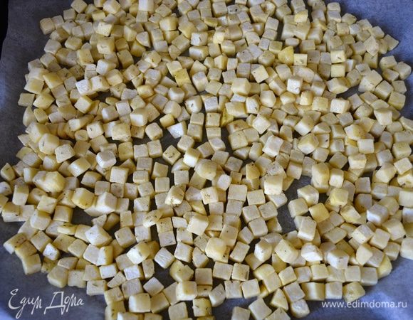 Выложить картофель в один слой на противень, застеленный пекарской бумагой.