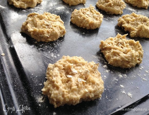 Чайной ложкой выложить тесто на противень застеленный бумагой для выпечки, на расстоянии 2-3см. Присыпать сверху овсяными хлопьями.