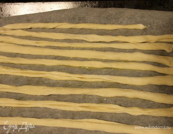 Нарезать тесто на тонкие полоски и каждую полоску скрутить в тонкий жгут движениями пальцев как будто скручиваем нитку. Так проделываем до конца. Выкладываем палочки на лист, смазанный маслом и ставим на среднюю полку духовки, разогретой до 180 С. Запекаем около 10-15 минут. В процессе выпечки пару раз сбрызгиваем палочки водой из пульверизатора.