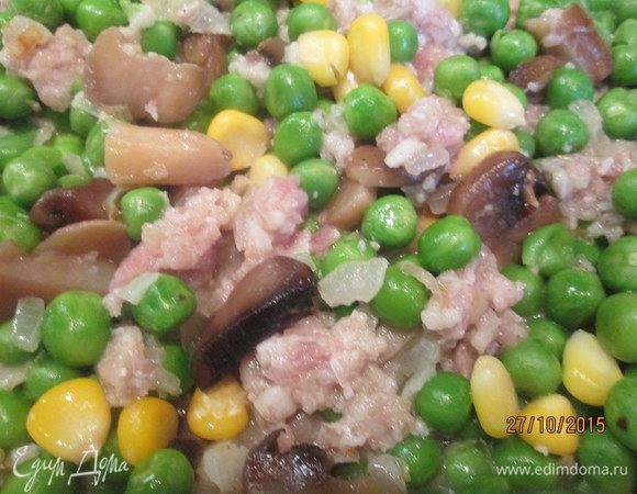 Добавляем к луку размороженный горошек, кукурузу, грибы, фарш и тушим под крышкой минут 10. При необходимости, добавляем воду, мелко нарезанный зеленый лук.