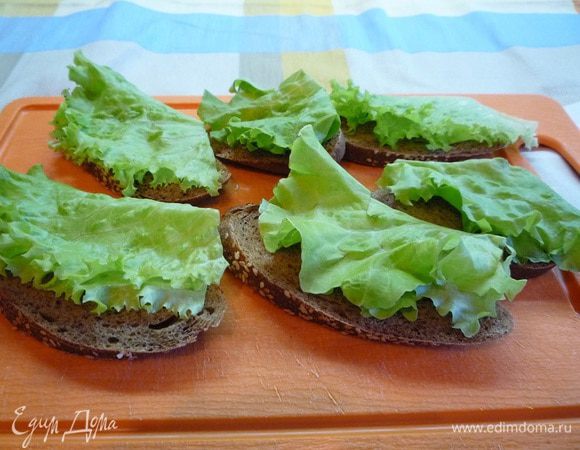 Яйца отварить и почистить.
Хлеб нарезать тонкими ломтиками, каждый ломтик смазать сливочным маслом, положить сверху листики салата и одному ломтику лосося на каждый бутерброд.