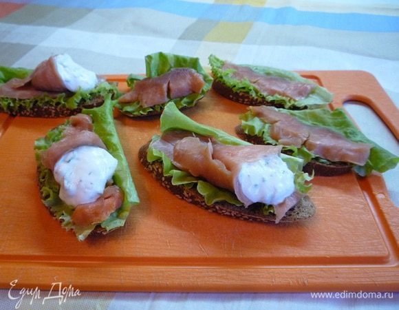Остальные ломтики рыбы свернуть конвертиком, положить в них по ложке йогурта и выложить их сверху на бутерброды.