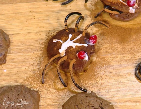 Присыпать паучков какао, глазурью нарисовать глазки, а на спинках различные узоры, сверху выложить ягоды смородины.