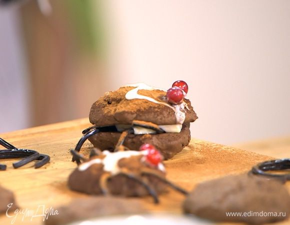 Оставшееся печенье остудить, у половины печенья смазать плоскую сторону кремом, разложить лакричные палочки, так чтобы их края свешивались, как лапки, и накрыть несмазанным печеньем. Посыпать сверху какао и сделать глазурью рисунок на спинках паучков.